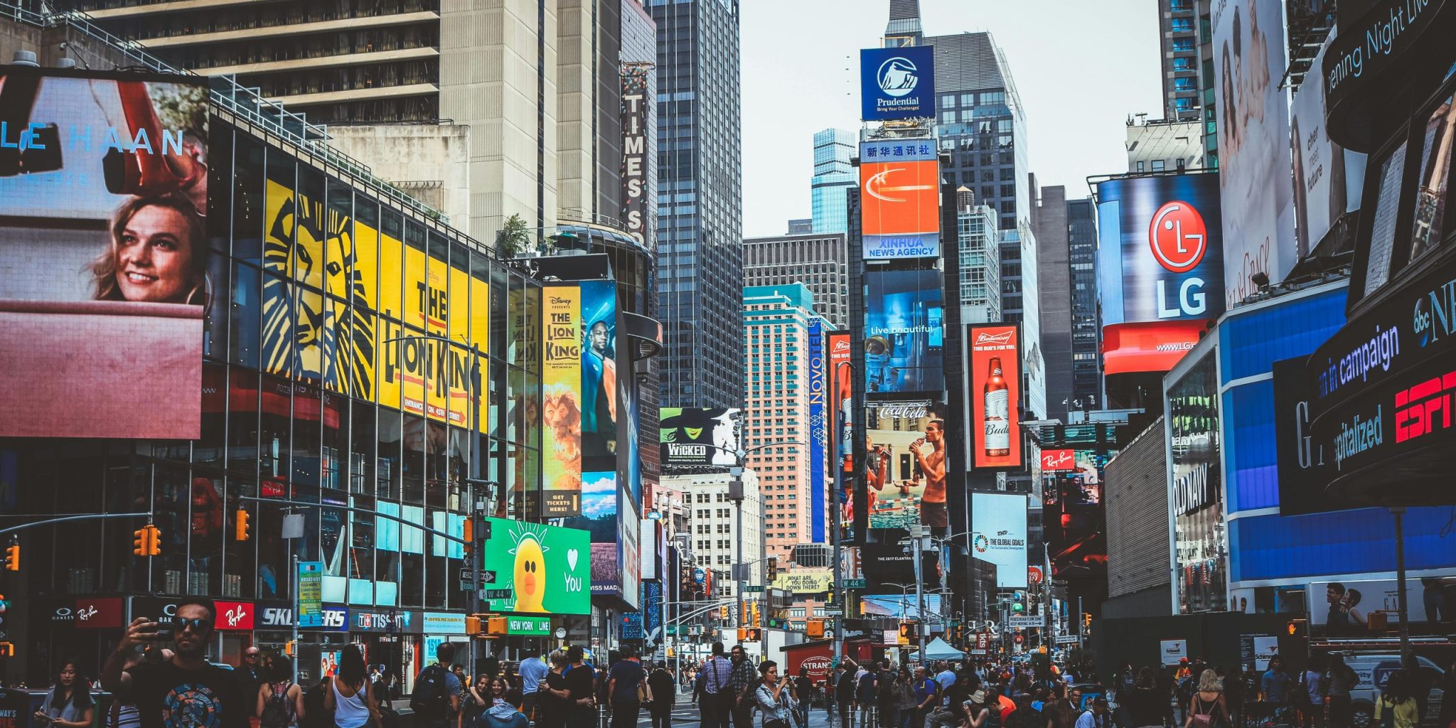 Bustling daytime view of Times Square with crowds, skyscrapers, and iconic billboards in New York City.