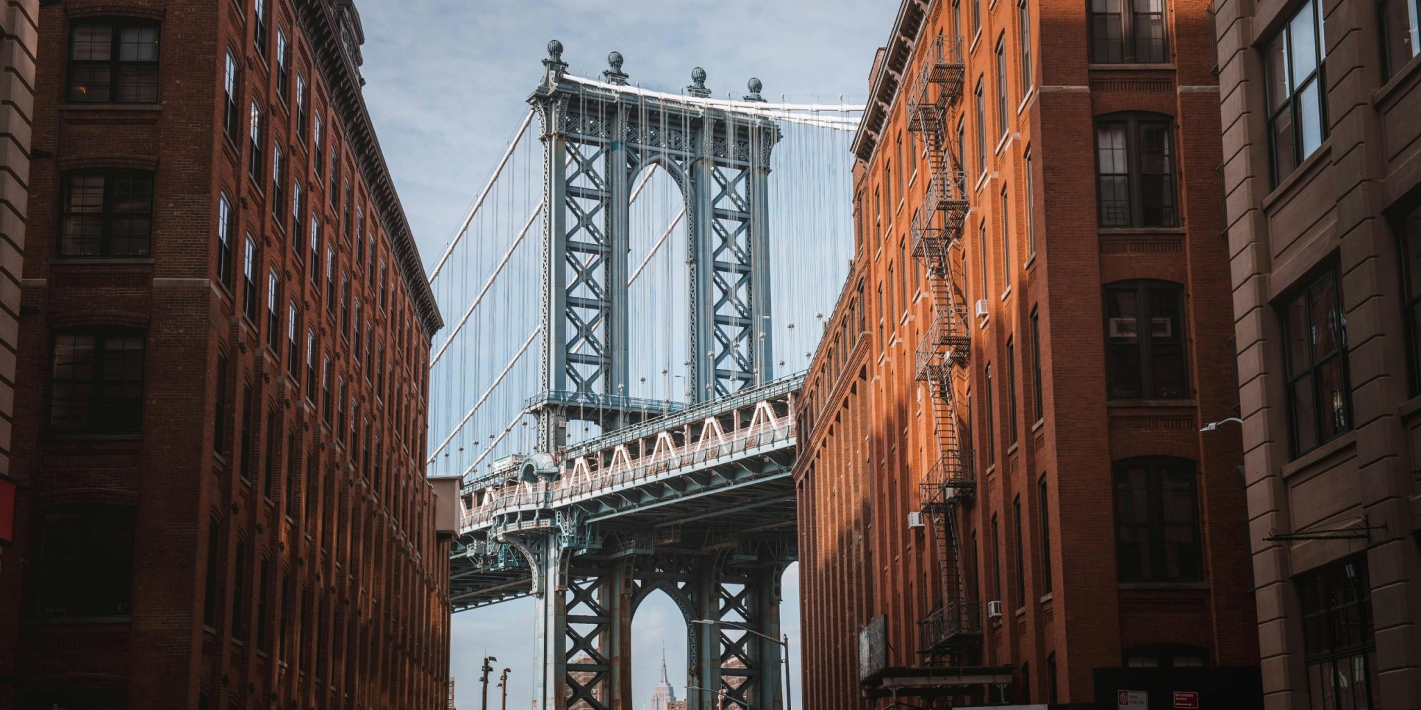 Stunning view of the Manhattan Bridge framed by red-brick buildings in New York City's DUMBO neighborhood.